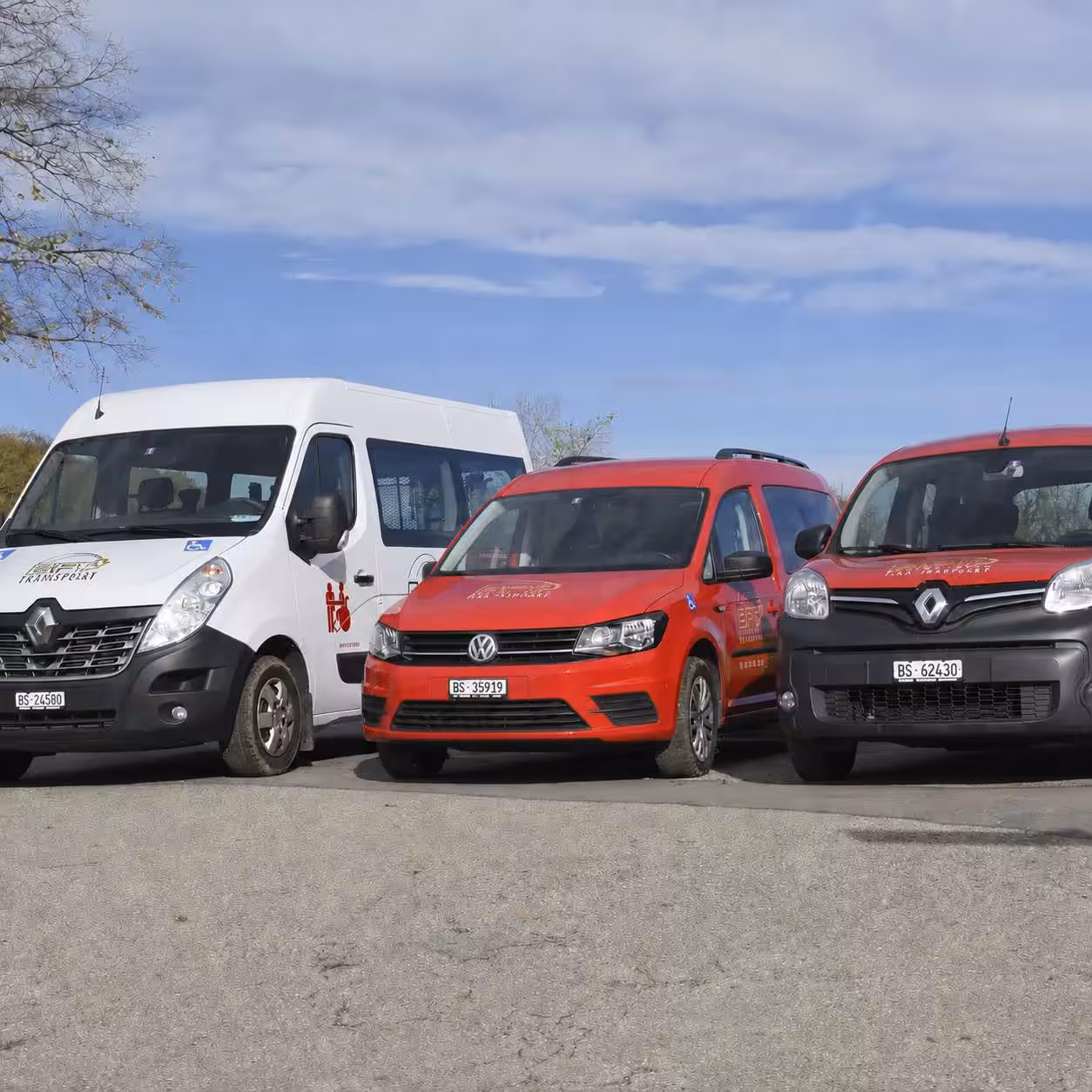 Drei Lieferwagen von Renault und Volkswagen auf einem Parkplatz unter blauem Himmel.